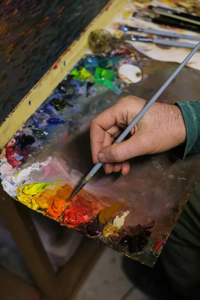 A Nepali artist carefully painting a traditional Thangka artwork by hand