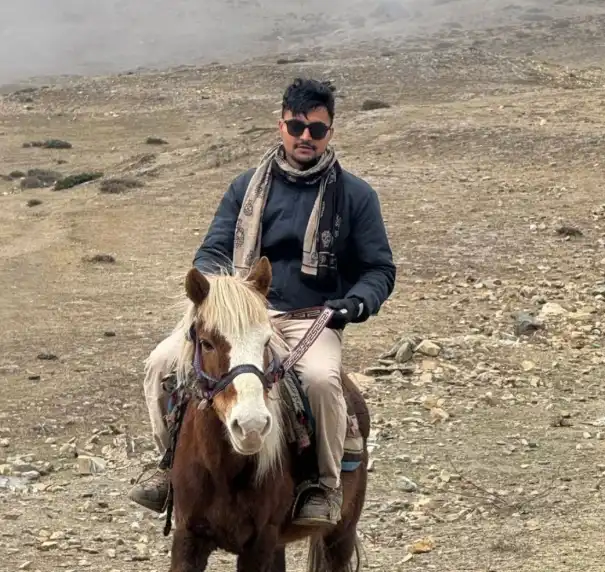 Tour officer riding a horse along the rugged trails of Nar Phu Valley, Nepal.