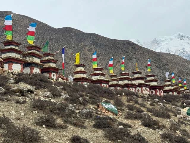 Square-shaped stupas with colorful Buddhist prayer flags fluttering at Tashi Lhakhang Monastery in the Nar Phu Valley