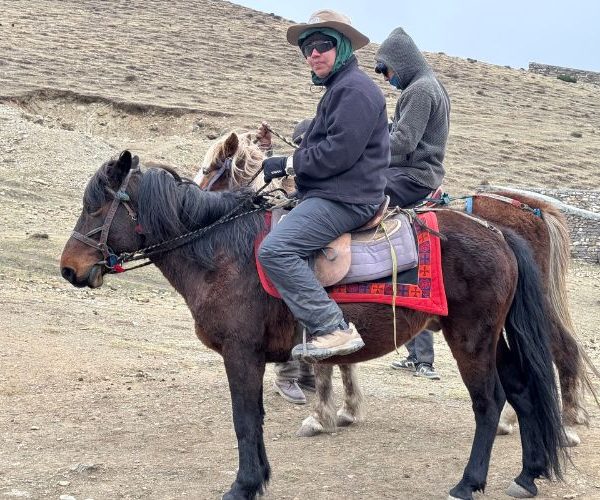 Traveler horse riding through the rugged trails of Nar Phu Valley, Nepal.